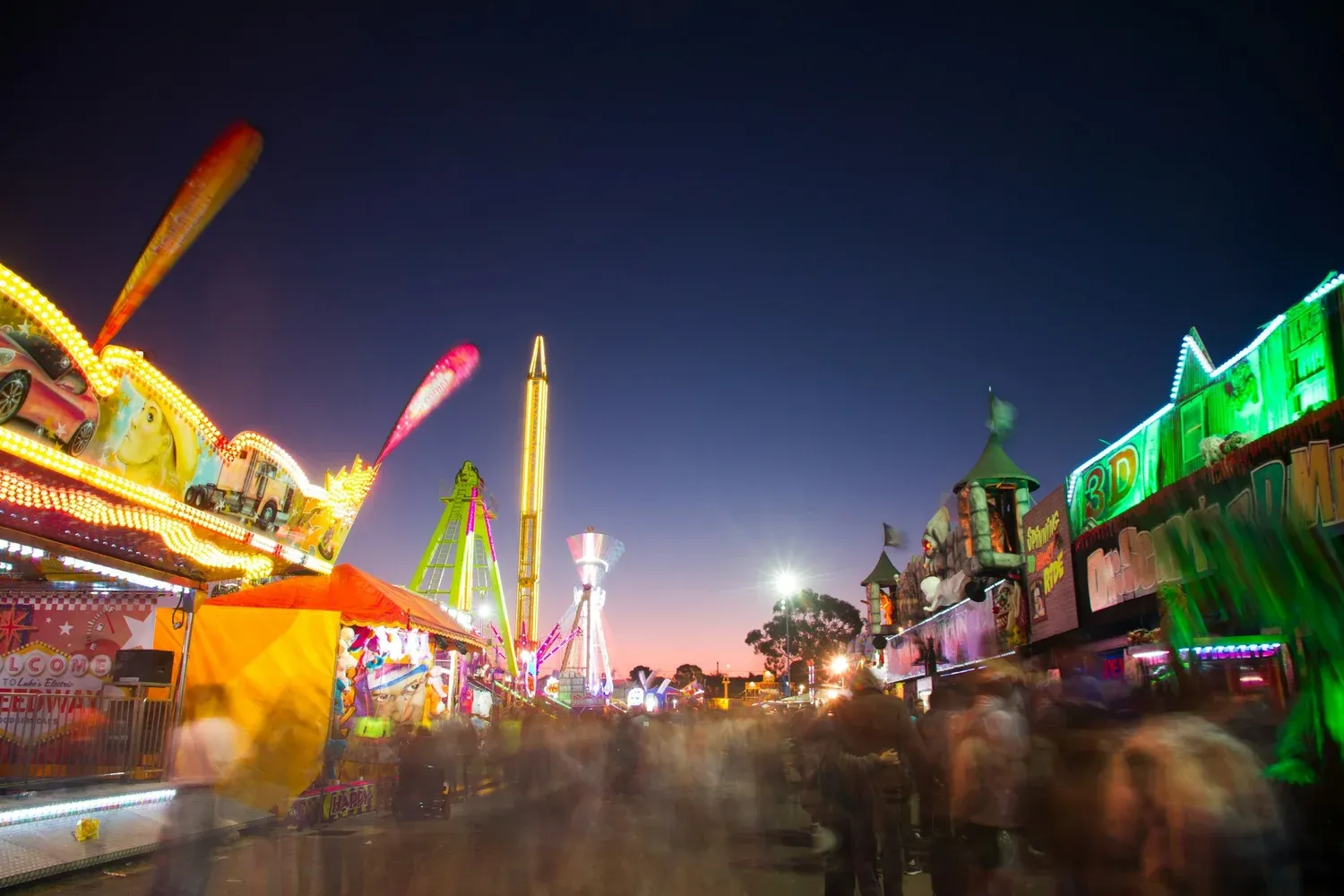 Night view of a lively carnival with bright lights and colorful rides.